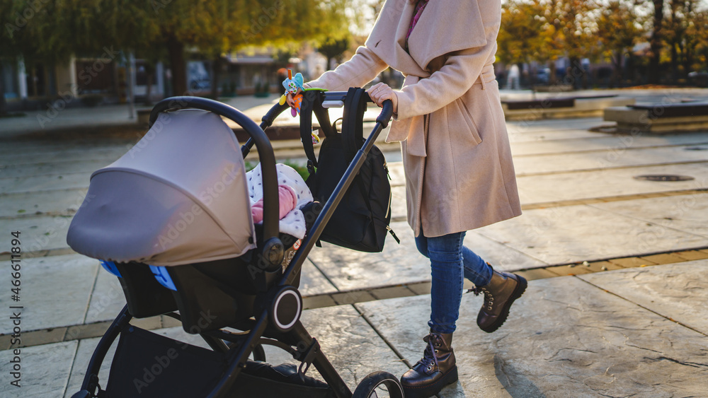 Close up on midsection of unknown caucasian woman mother pushing stroller with baby in the city in day motherhood concept