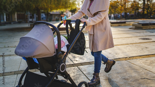 Close up on midsection of unknown caucasian woman mother pushing stroller with baby in the city in day motherhood concept photo