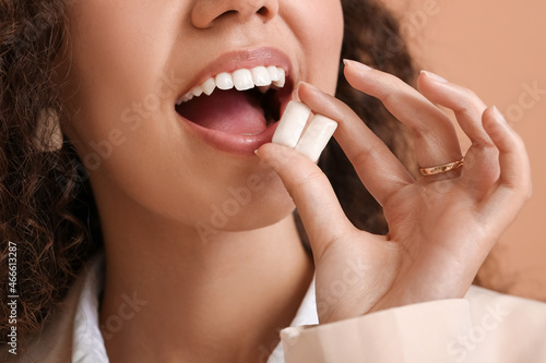 Papier peint Beautiful African-American woman with chewing gum on color background, closeup