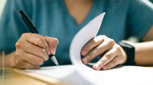 Close up image of person with pen signing contract at desk, Conclusion of agreement with business document, taking bank loan, making financial deal with partner at negotiation. photo