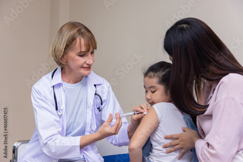 Pediatrician doctor doing vaccination of a little girl in hospital.