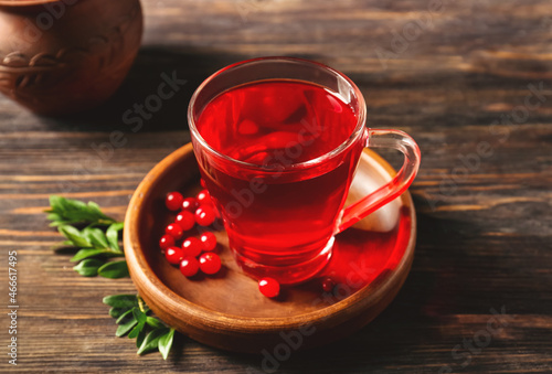 Glass cup of tasty lingonberry tea on wooden background