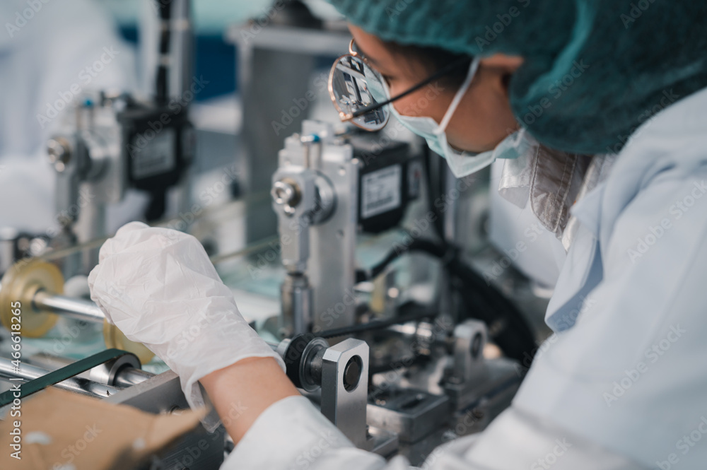 Both male and female Asian scientists are outfitted with protective gear. Examining the factory's machinery and materials used in the mask-making process. Covid 19 is a piece of preventive equipment. Both male and female Asian scientists are outfitted with protective gear. Examining the factory's machinery and materials used in the mask-making process. Covid 19 is a piece of preventive equipment.