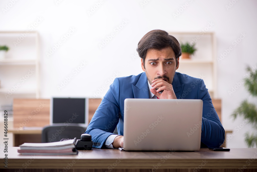 Young male employee sitting at workplace Young male employee sitting at workplace