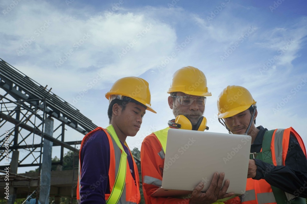 The senior engineering manager with the construction teamwork in full safety plans their workflow using notebook computers on the home construction site.action plant safety teamwork concept. The senior engineering manager with the construction teamwork in full safety plans their workflow using notebook computers on the home construction site.action plant safety teamwork concept.
