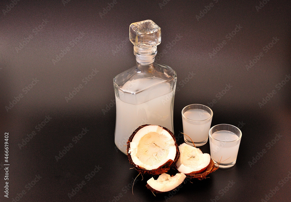 Homemade coconut liqueur and broken ripe nut on black isolated background. Homemade coconut liqueur and broken ripe nut on black isolated background.