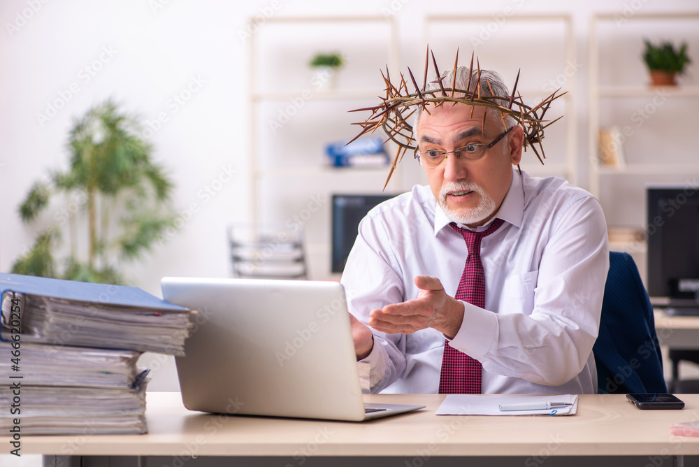 Fototapeta premium Old male employee wearing prickly wreath on head