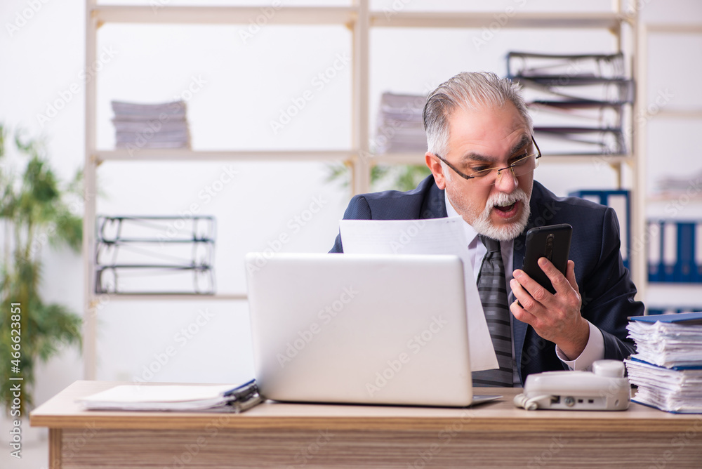 Old male employee working at workplace Old male employee working at workplace