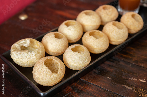 Fototapeta Naklejka Na Ścianę i Meble -  Popular Indian food named Pani puri served on table. Pani Puri is a combination of street food recipe made with small puri balls filled with spiced and mashed aloo and a specially made spiced water.