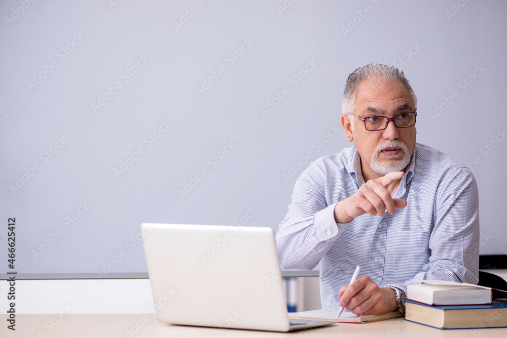 Old male teacher in front of whiteboard Old male teacher in front of whiteboard