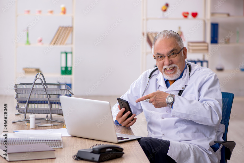 Old male doctor working in the clinic Old male doctor working in the clinic