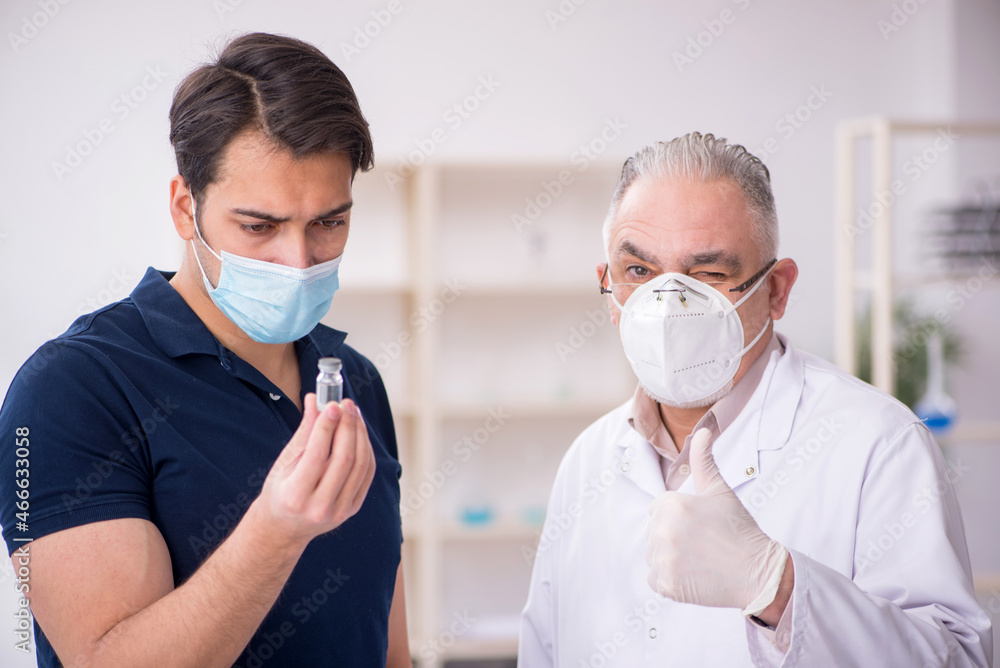 Young male patient visiting old male doctor in vaccination conce