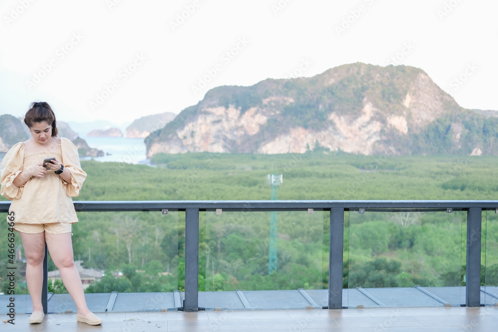 Asian woman holding a smartphone at a tourist attraction Tourism, beautiful mountains and sky in Thailand