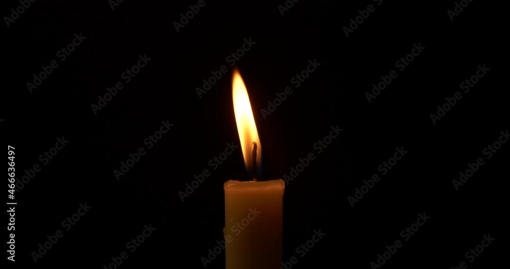 Close-up burning single candle flame isolated on black background, 4K video Close-up burning single candle flame isolated on black background, 4K video