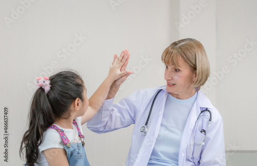 Female doctor giving high five to a little cute girl. Kid on consultation at the pediatrician. Healthcare and medicine concepts