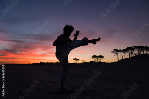 silueta de hombre practicando artes marciales al atardecer en la playa photo