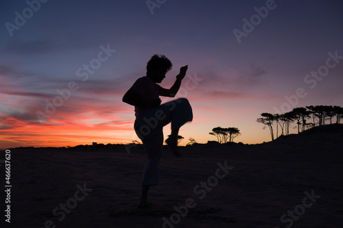 silueta de hombre practicando artes marciales al atardecer en la playa © Galdys V