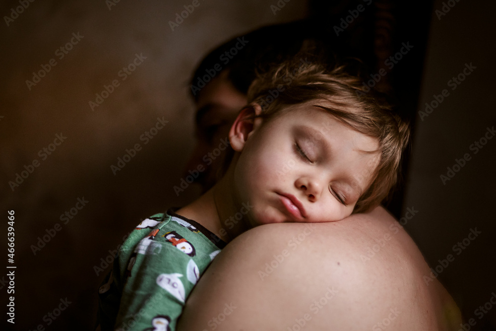 Cute caucasian boy sleeping putting head on father's shoulder. Fatherhood concept. Parent care, support and safety