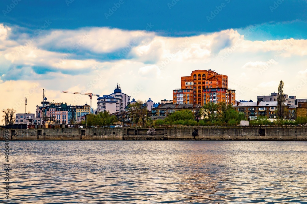 Houses on the Dnieper embankment in Kiev. City skyline. Water surface. City embankment. The Dnieper River in Ukraine. Cloudy weather. Dwelling houses. Travel business. Houses on the Dnieper embankment in Kiev. City skyline. Water surface. City embankment. The Dnieper River in Ukraine. Cloudy weather. Dwelling houses. Travel business.