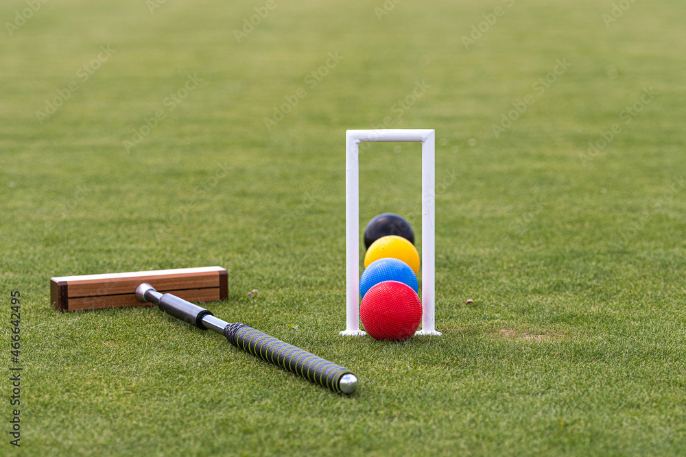 croquet mallet, wicket and colorful balls on a lawn Photos | Adobe Stock