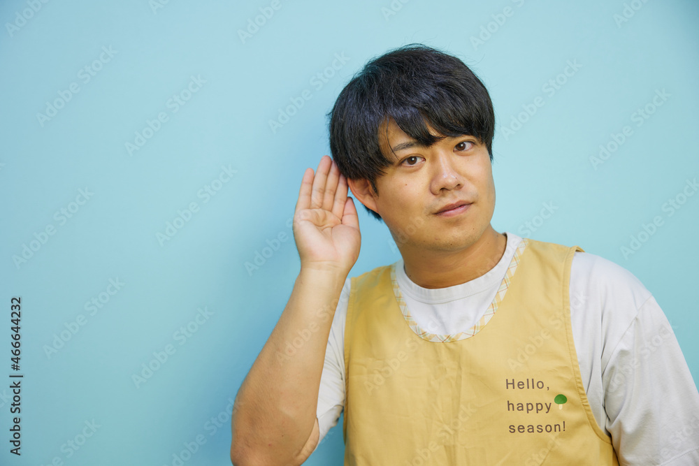 コピースペースに向かって耳を傾けるエプロンを着たアジア人男性 コピースペースに向かって耳を傾けるエプロンを着たアジア人男性