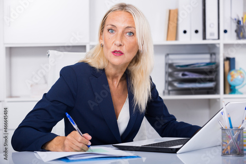 Photos Portrait of mature serious business woman at working place in office