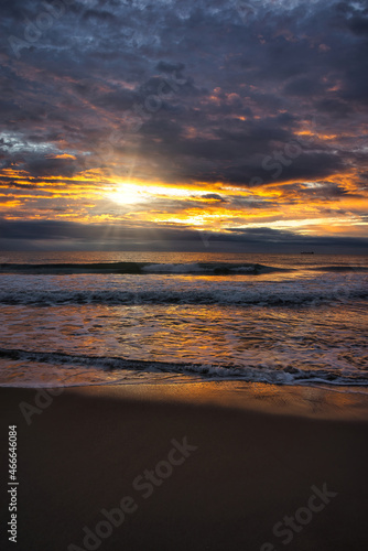 A beautiful and cloudy sunrise from the shore of a beach © vicenfoto