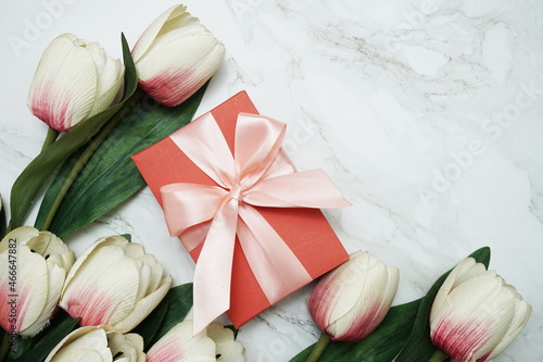 Gift boxes with pink ribbon and tulip flower bouquet on marble background