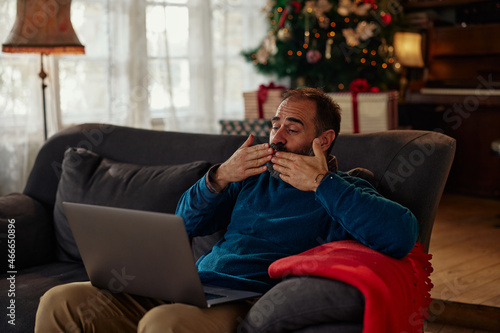 Man relaxing on sofa during Christmas and having video call