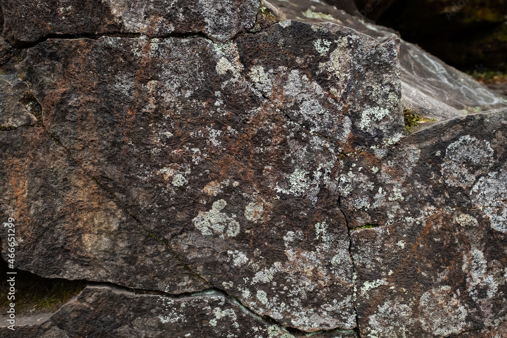 The texture of a natural stone wall with lichen.