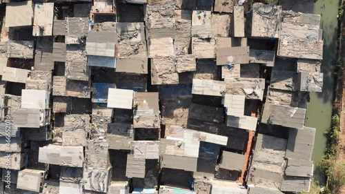 Top aerial drone movement shot of the closely packed urban slums or shanty town housing situated next to sewage in suburban part of the Mumbai city