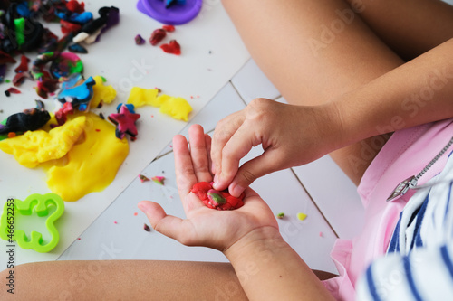 Closeup portrait of kid hands playing colorful dough photo