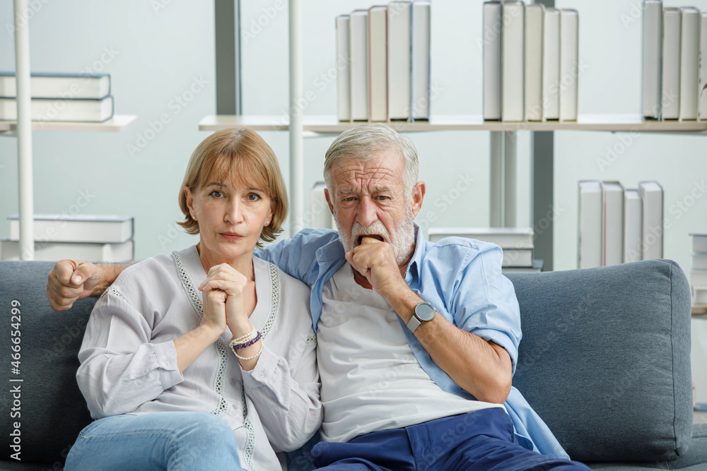Caucasian old senior grandparents couple in casual wear gray bearded and hair grandpa husband and grandma wife sitting stress horror thrilling worrying watching scary movie together at home