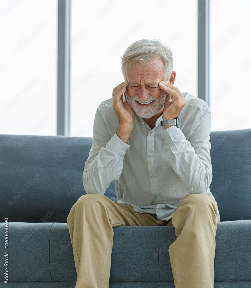 Caucasian old senior elderly unhealthy sick ill gray bearded and hair male grandfather sitting on sofa at home alone holding hands on head suffering from emergency painful headache migraine problem Caucasian old senior elderly unhealthy sick ill gray bearded and hair male grandfather sitting on sofa at home alone holding hands on head suffering from emergency painful headache migraine problem