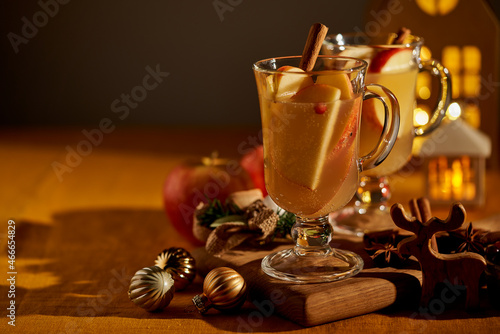 Two glasses of hot christmas winter apple gluhwein. Alcohol white mulled wine with cinnamon, cranberry. Apple cider. Selective focus, dark background with hard light shadows photo