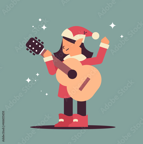 elf in uniform with musical instrument girl santa helper playing guitar happy new year christmas holidays celebration