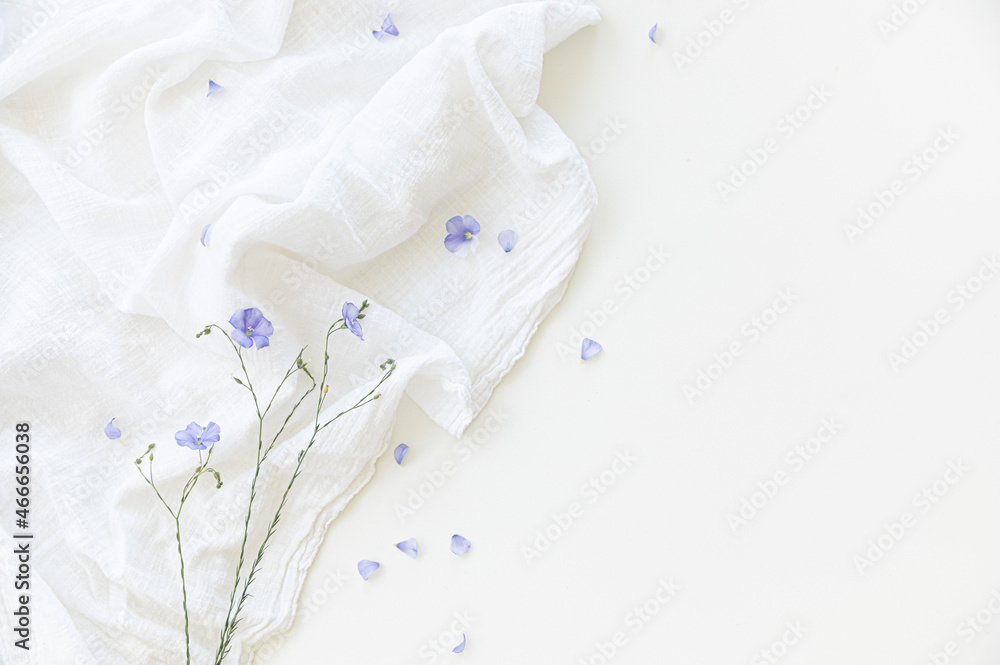Blooming flax flowers on a white background on light-colored textiles. Blooming flax flowers on a white background on light-colored textiles.