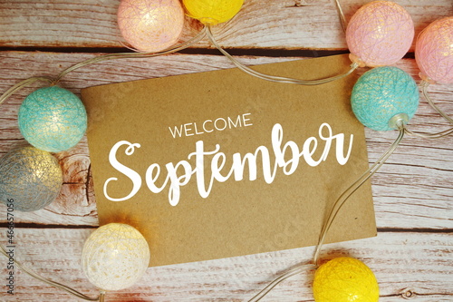 Welcome September card typography text with LED cotton ball on wooden background