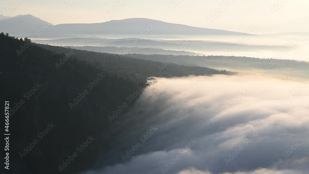 Ocean of clouds slowly drifting among tree tops in the morning. Aerial view of scenic sunrise in mountains Ocean of clouds slowly drifting among tree tops in the morning. Aerial view of scenic sunrise in mountains