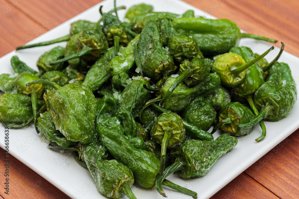 Baked green peppers with crystals of salt. Portion of fresh made Pimientos de Padron. Traditional spanish snack. Baked green peppers with crystals of salt. Portion of fresh made Pimientos de Padron. Traditional spanish snack.