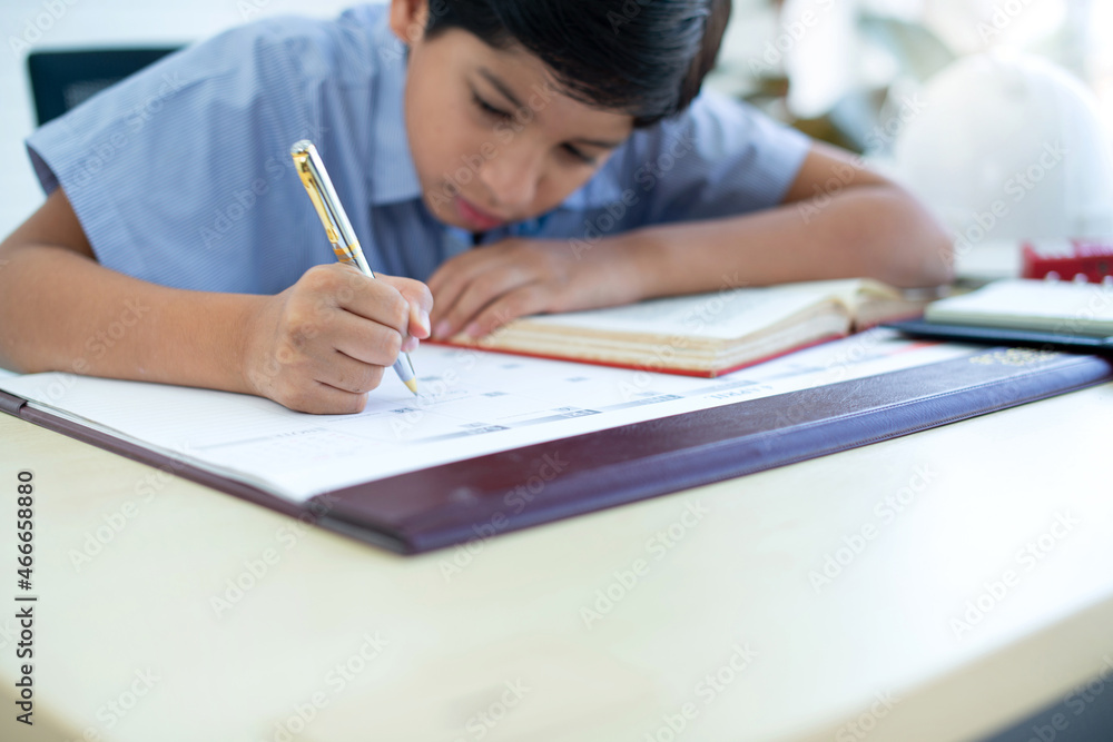 Indian boy doing his homework, Little boy learns with his books in study room, selective focus Indian boy doing his homework, Little boy learns with his books in study room, selective focus