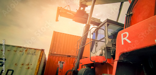Reach stacker lifting container. Forklift truck handling container at dock. Reach stacker vehicle. Container transport in logistic industry. Cargo and shipping business. Import and export logistic. photo