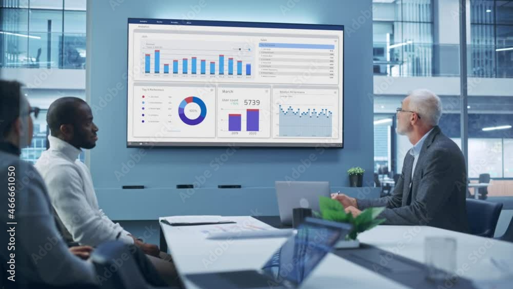 Office Conference Room Meeting: Group of Professional Entrepreneurs, Investors Talk, Use TV Screen with Infographics, Analysing Charts, Graphs, Statistics. Businesspeople Discuss Investment Strategy Office Conference Room Meeting: Group of Professional Entrepreneurs, Investors Talk, Use TV Screen with Infographics, Analysing Charts, Graphs, Statistics. Businesspeople Discuss Investment Strategy