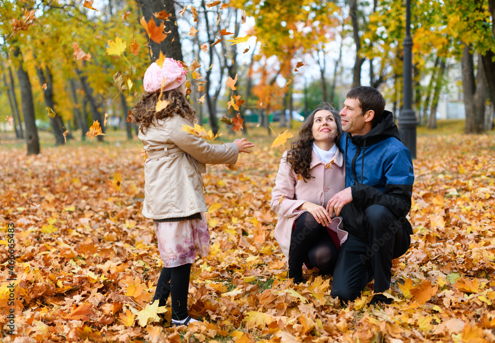 Family portrait in an autumn park. Happy people playing with fallen yellow leaves. Family portrait in an autumn park. Happy people playing with fallen yellow leaves.
