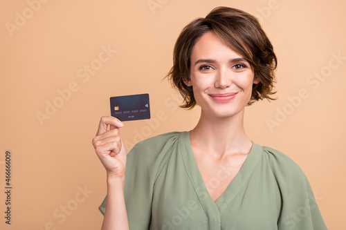 Photo of cheerful happy young woman smile hold hands credit card buy shop isolated on beige color background photo