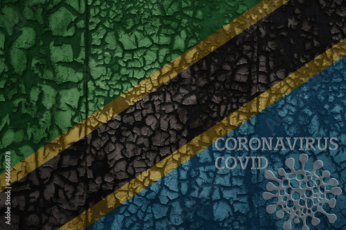 flag of tanzania on a old metal rusty cracked wall with text coronavirus, covid, and virus picture.