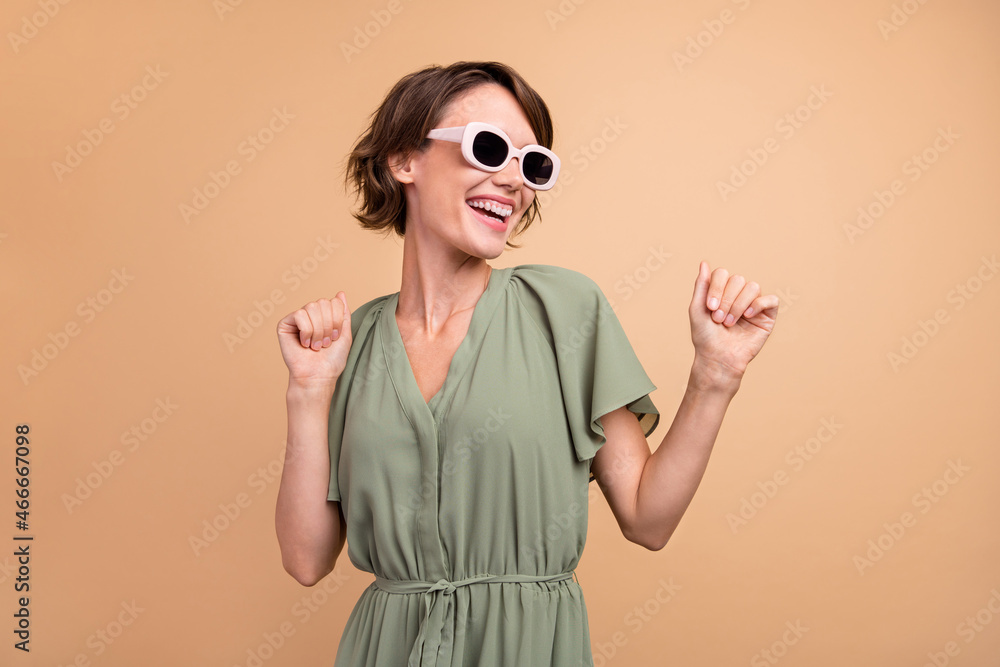 Photo of positive attractive young woman enjoy look empty space dance wear dress isolated on beige color background Photo of positive attractive young woman enjoy look empty space dance wear dress isolated on beige color background