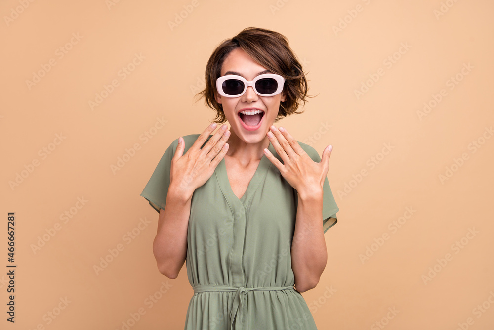 Photo of shocked excited happy young woman hand face wear sunglass sale season isolated on beige color background Photo of shocked excited happy young woman hand face wear sunglass sale season isolated on beige color background