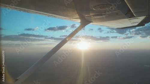Man flying a small Cessna plane during the sunrise.