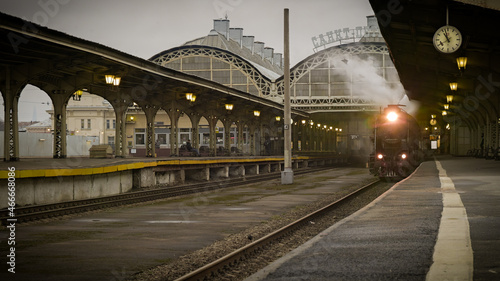 Vintage steam locomotive in departs from old railway station.